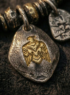 Close-up of hammered vintage metal pendant with gold eagle totem emblem