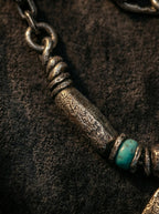 Close-up of cylindrical vintage metal bead and turquoise accent on necklace