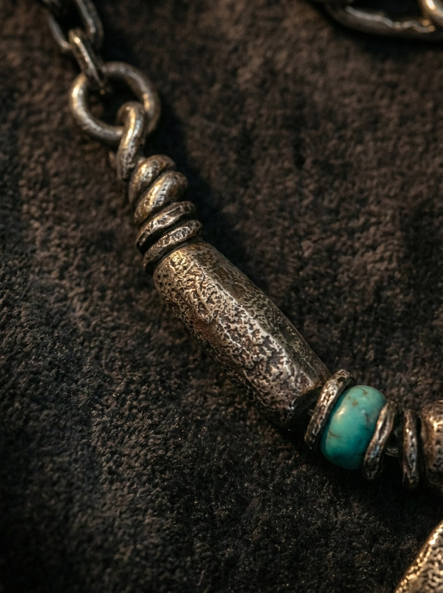 Close-up of cylindrical vintage metal bead and turquoise accent on necklace