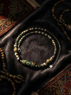 Tibetan Forest Elegance necklace featuring green agate Dzi bead and natural gemstone strands on dark velvet