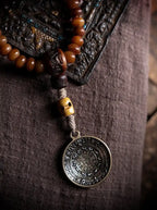 Close-up of Tibetan Nine Palace Bagua bronze amulet pendant on antiqued yak bone guru bead