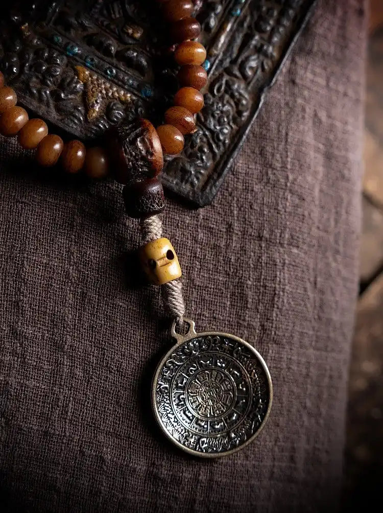 Close-up of Tibetan Nine Palace Bagua bronze amulet pendant on antiqued yak bone guru bead